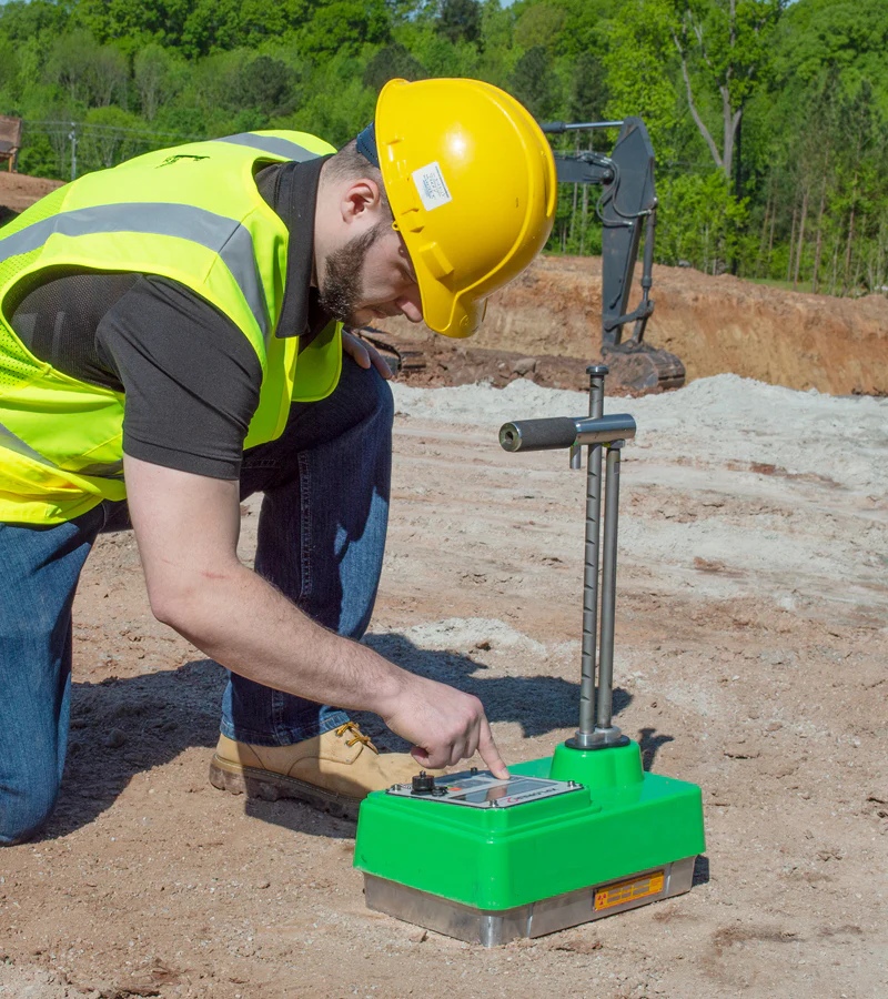 An image of a technician using a nuclear density gauge to locate underground water sources.