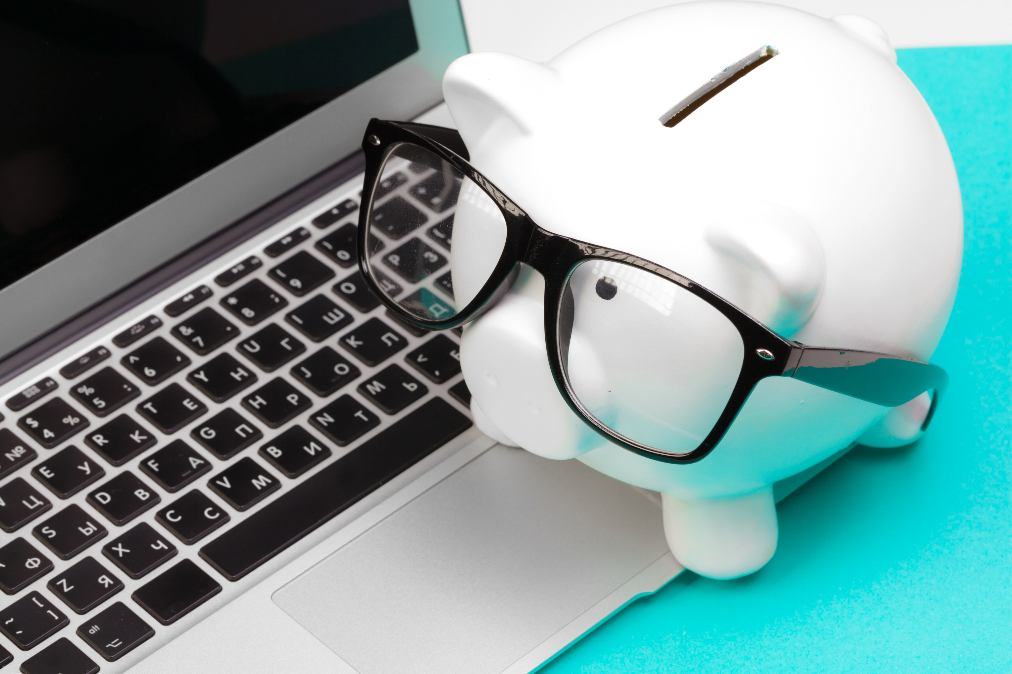 Piggybank with glasses and a laptop