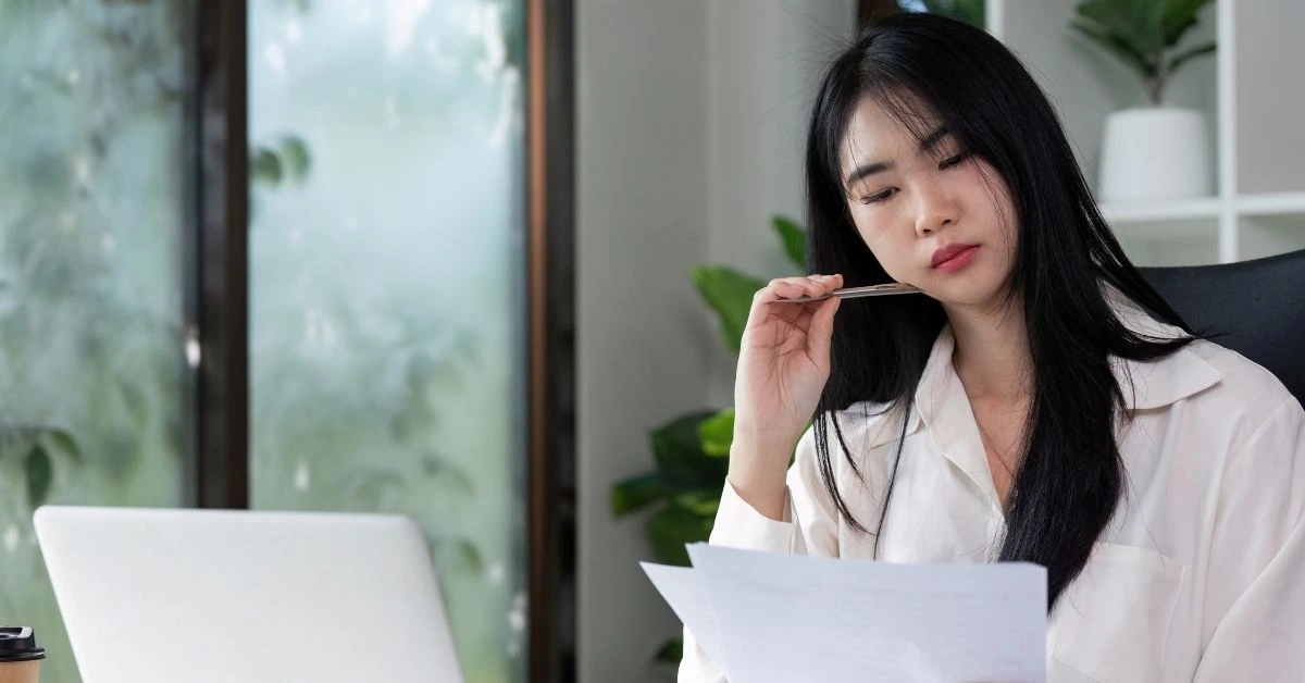 Woman reviewing financial documents on laptop to understand how do I pay myself from my LLC.