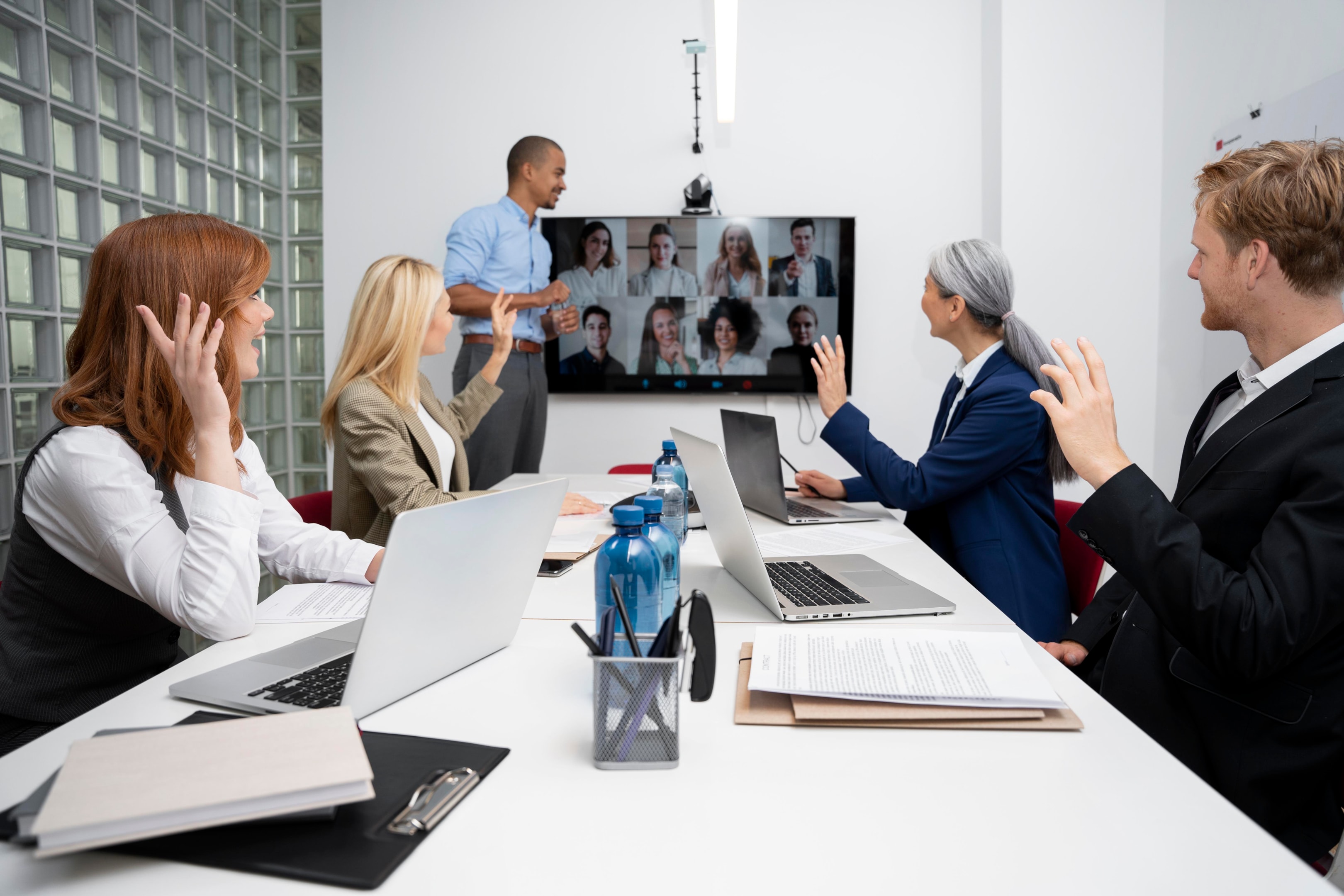 Hybrid team participates in a video meeting using integrated office communication systems, combining in-person and remote collaboration with a business phone system for seamless interaction.