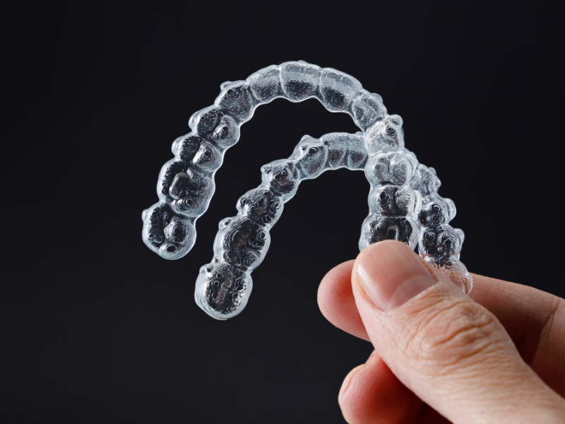 Image of someone holding clear removable retainers.