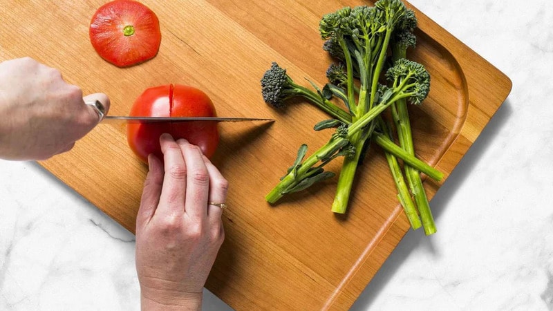 A man is cutting tomato on marble counter