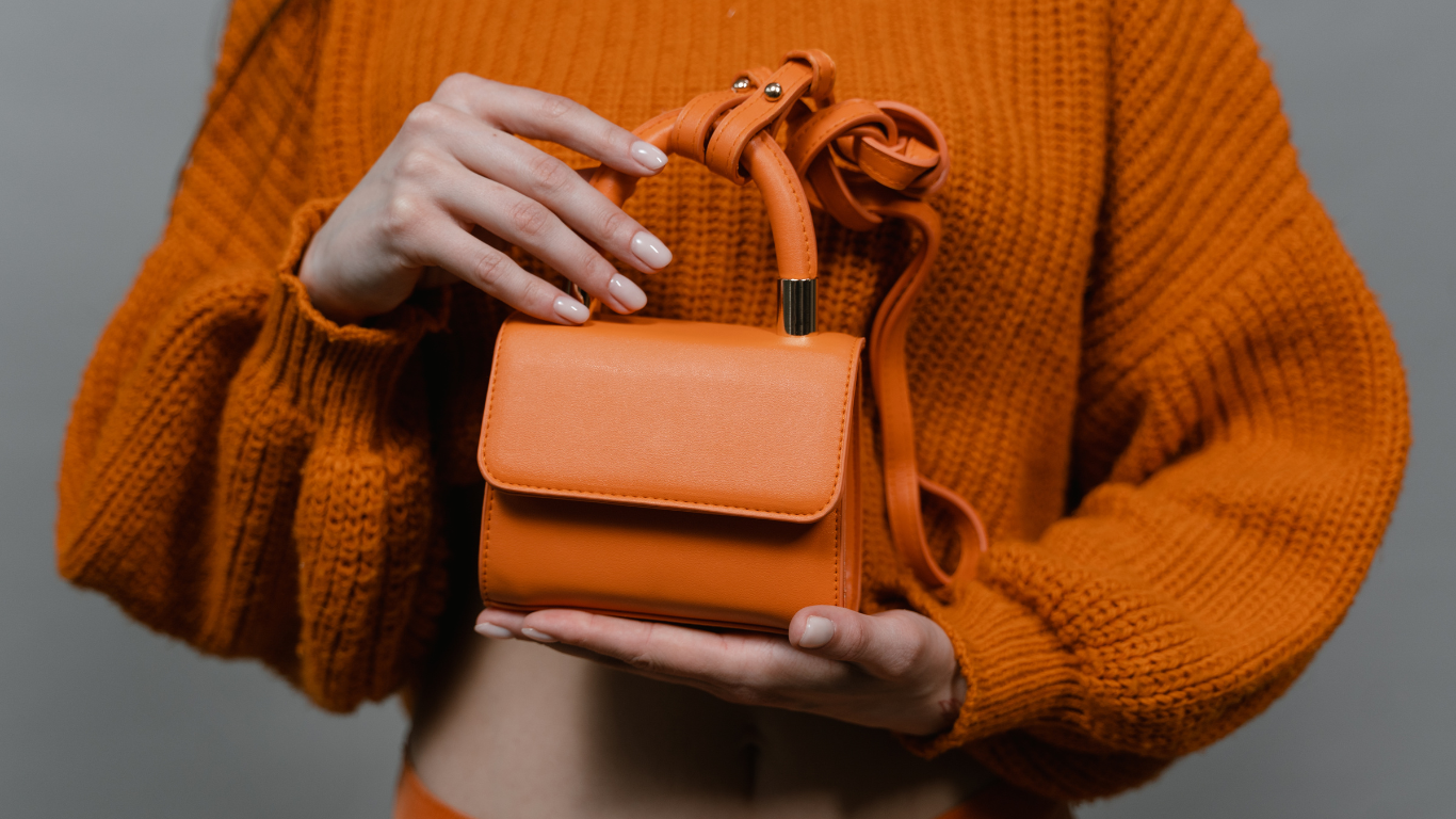 orange handbag carried by woman in orange sweater