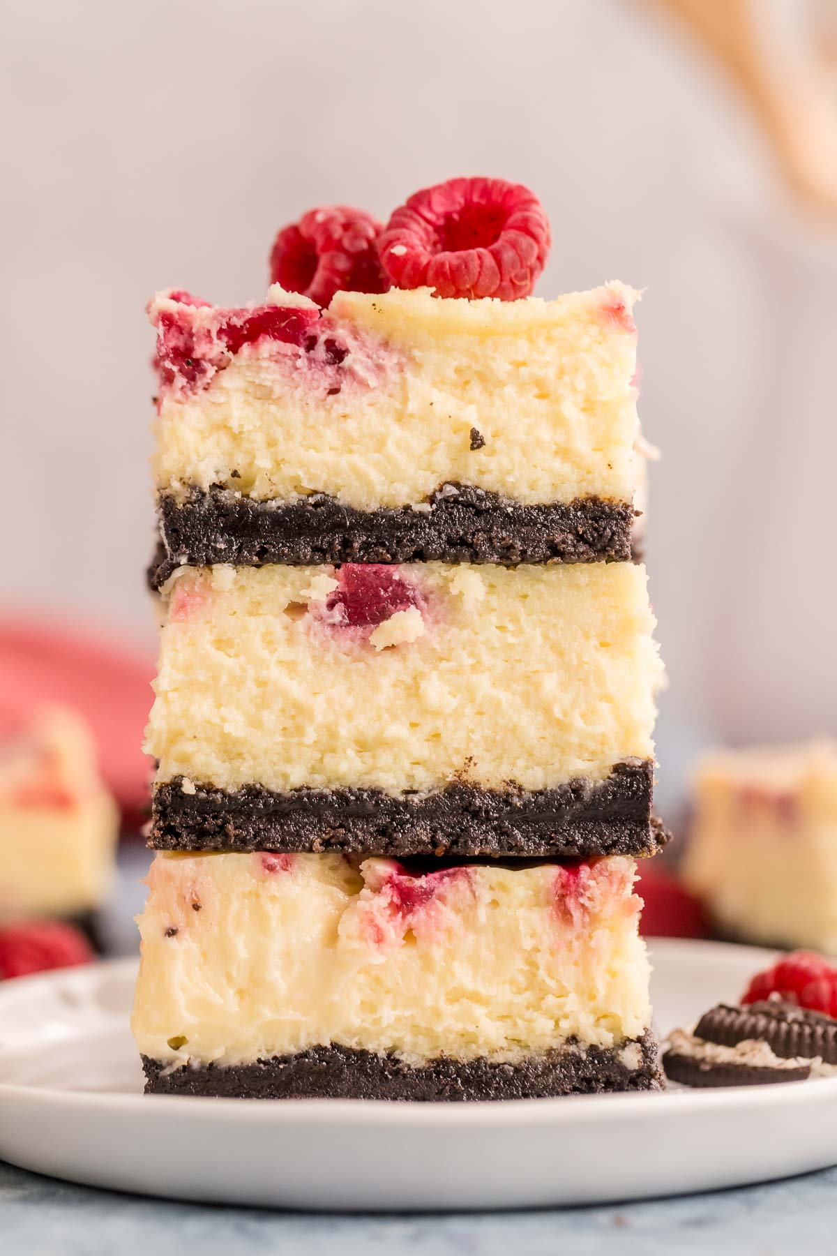 three white chocolate raspberry cheesecake bars stacked on top of each other 