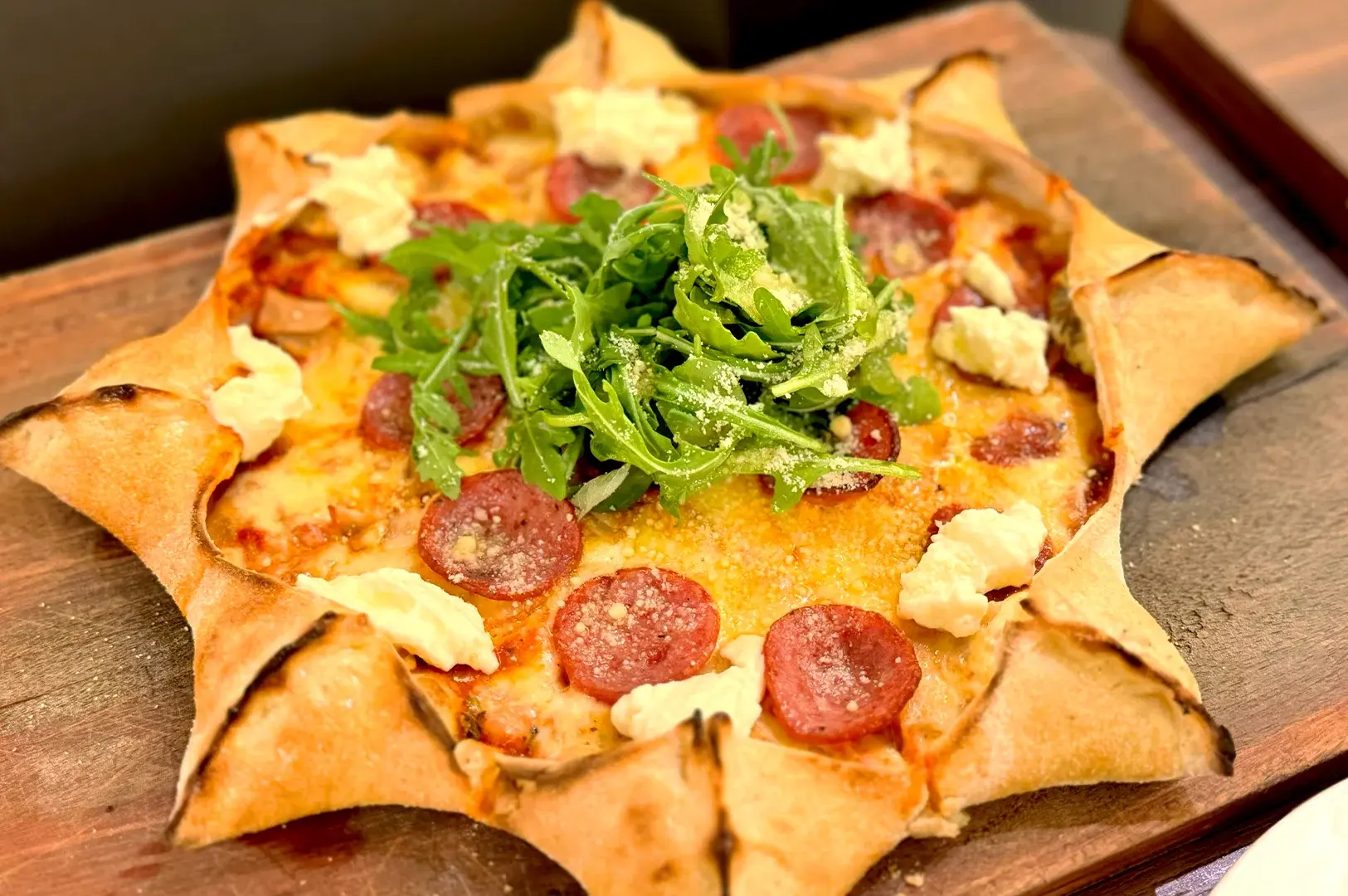 Signature Positano pizza, a star-shaped Italian specialty featuring fresh arugula and cheese, served at the popular halal-certified Positano Risto in Singapore's Kampong Glam district.