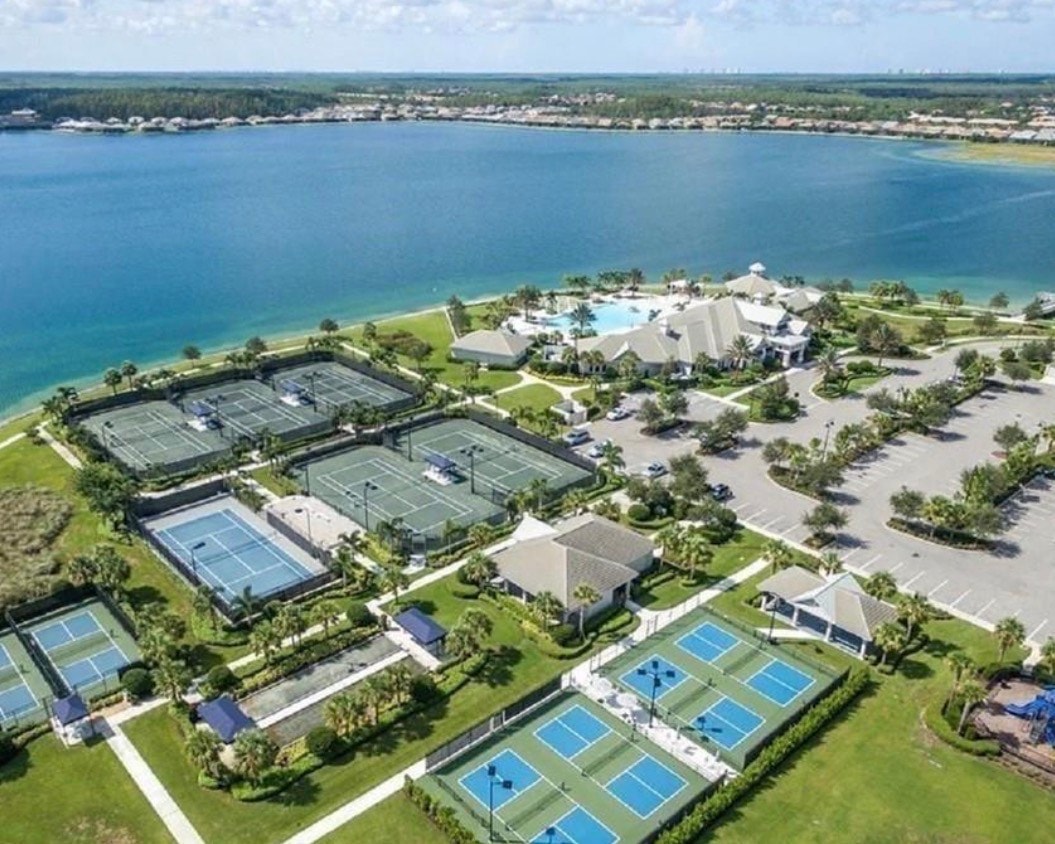 The image depicts a cozy community gathering area in a gated community, featuring a fire pit surrounded by comfortable seating, all overlooking a serene lake. This beautiful setting is part of Corkscrew Shores, where residents enjoy access to various amenities including walking trails and a resort-style pool.