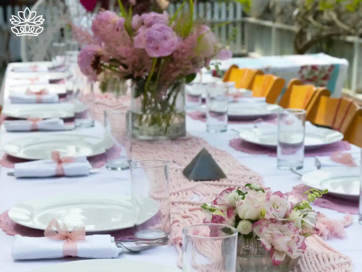 Elegant table setting for a baby shower with pink floral centrepieces and neatly arranged place settings, creating a charming atmosphere. Fabulous Flowers and Gifts: Baby Shower Flowers Collection