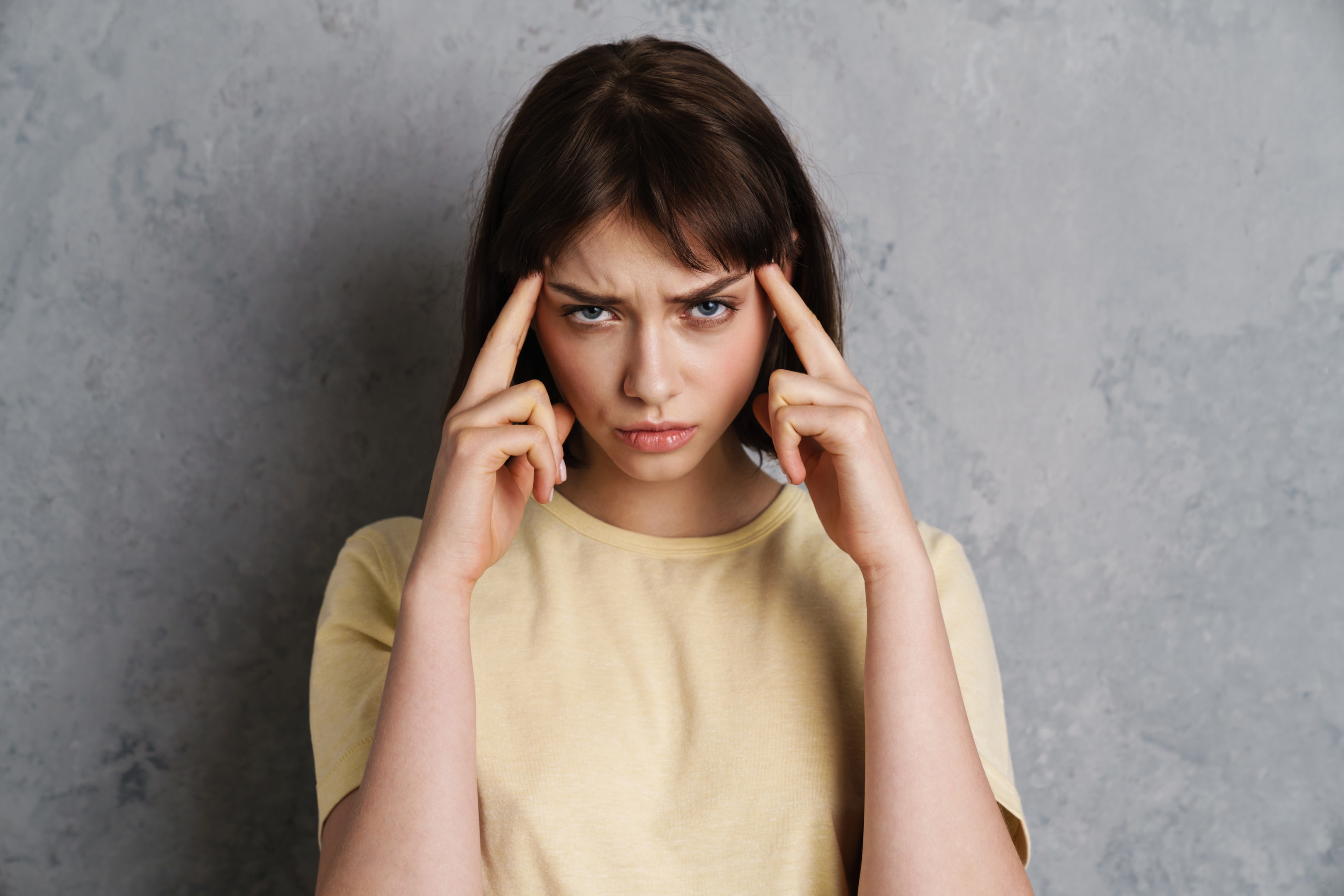 A woman pressing her fingers to her temples with a concentrated and distressed expression, illustrating the intense mental focus often required to utilize Managing Panic Attacks in The Woodlands during an episode.