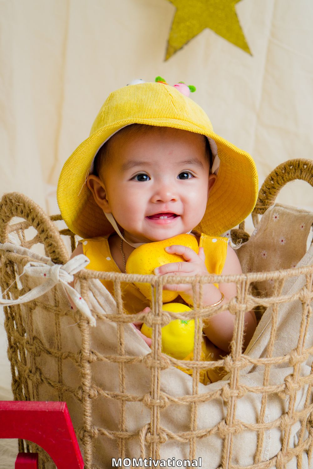 Gorgeous baby boy in a basket with a yellow hat