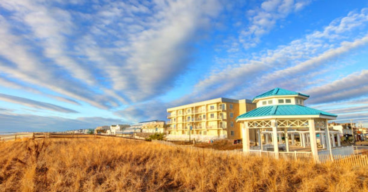 Oceanfront gazebo with blue roof in Sea Isle City, NJ surrounded by golden beach grass and rental condos near the shoreline.