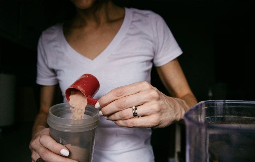 Mulher preparando shake de suplemento alimentar. Foto de Kelly Sikkema, Unsplash.
