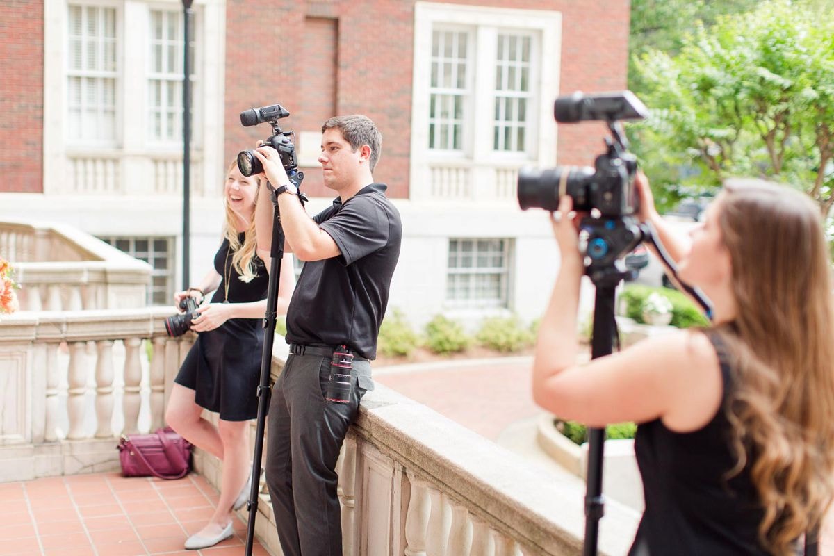 A professional wedding photographer and videographer team working together on a wedding shoot.