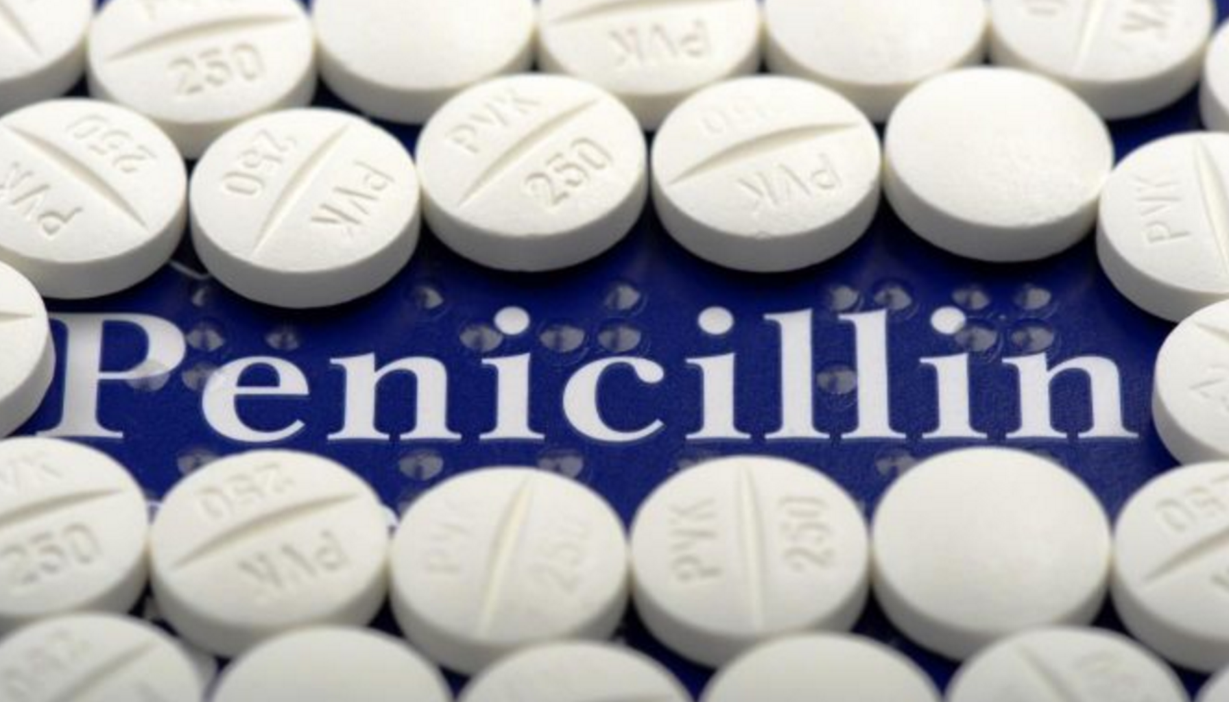Hvite penicillin-tabletter lagt i sirkel på blå bakgrunn, brukt som antibiotika mot bakterielle infeksjoner.