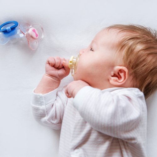 baby with a dummy in their mouth and spare dummies