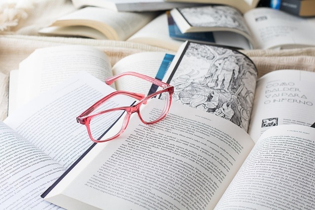 An image of several books and a pair of glasses.